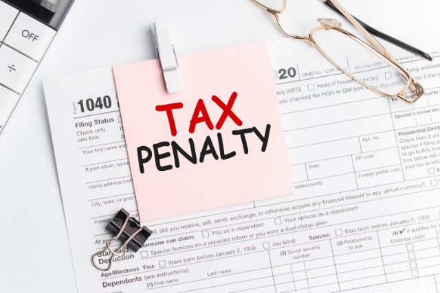 書類の上に置かれたTAX PENALTYと書かれたピンク色の付箋