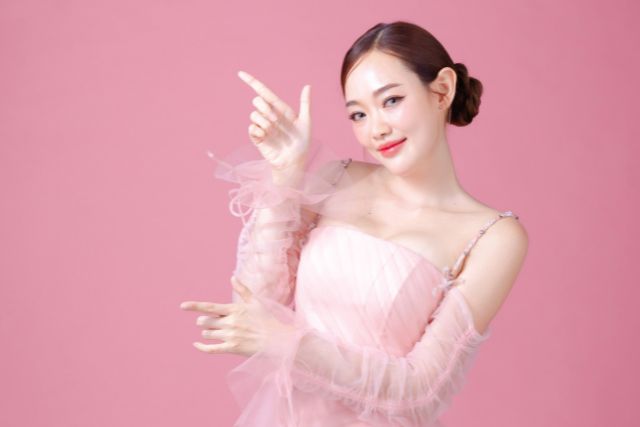 空間を指さすピンクのドレスを着た女性