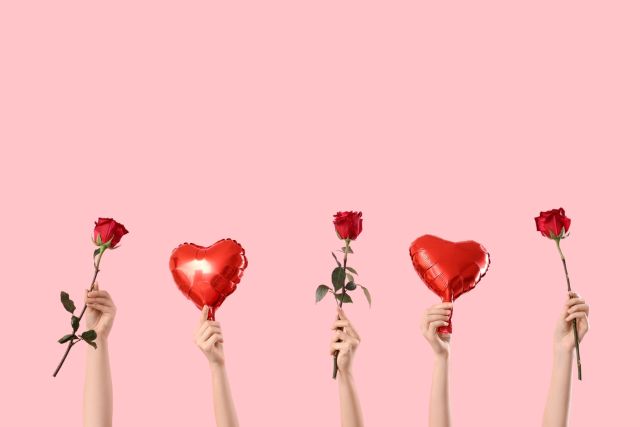 ピンクの背景に薔薇とハートの風船を持った5本の手