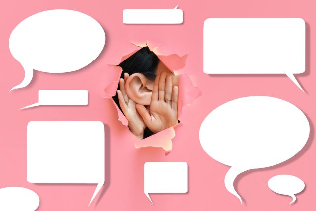 ピンクの壁に貼られた吹き出しと中からのぞかせる女性の耳