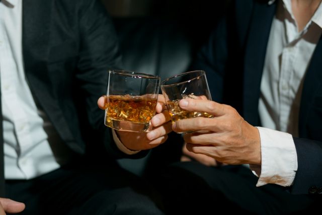乾杯するスーツの男性2人の手