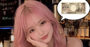 若い淡いピンク色の髪の色のウェーブロングヘアのかわいい女性が頬付えをついている