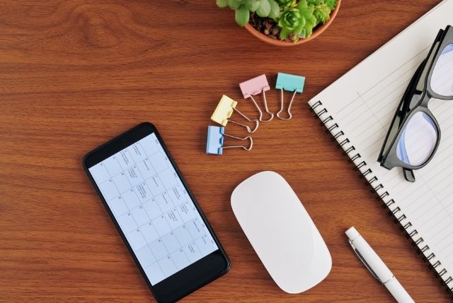 ノートとスマホに表示されたスケジュール