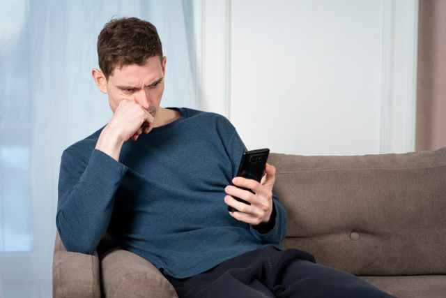 ソファで携帯を見る男性