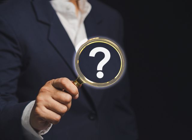 ハテナマークがついた虫眼鏡を持つ男性