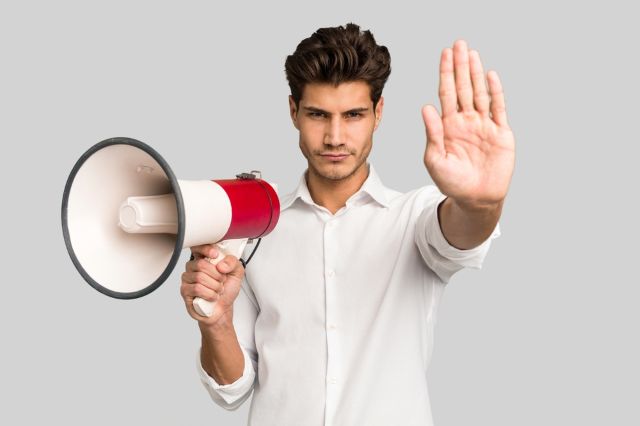 メガホンを持って手のひらを向ける男性