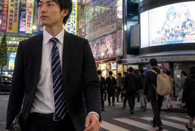 東京の夜の街を歩くスーツ姿の日本人男性