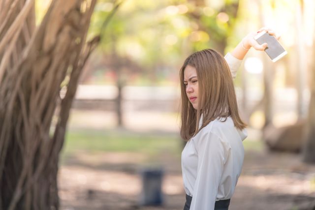 携帯を上に投げようとしている女性