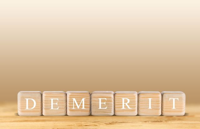 ベージュの背景の前にあるDEMERITと書かれたブロック