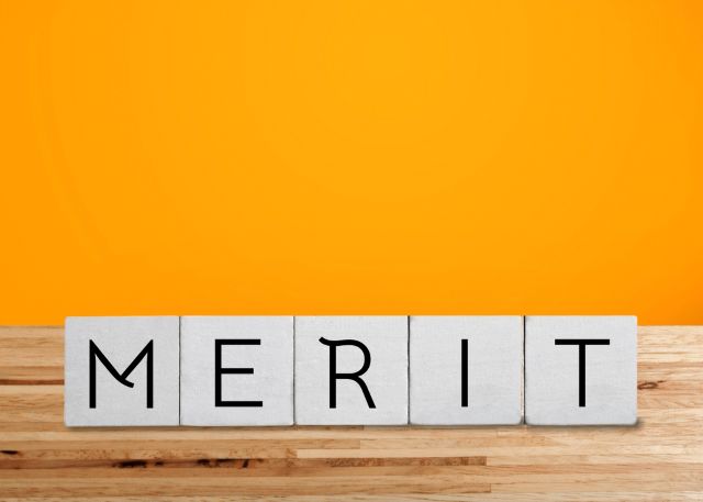 オレンジの背景の前にあるMERITとかかれたブロック