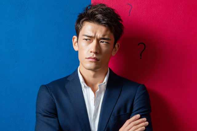 赤と青の背景の前で悩む男性