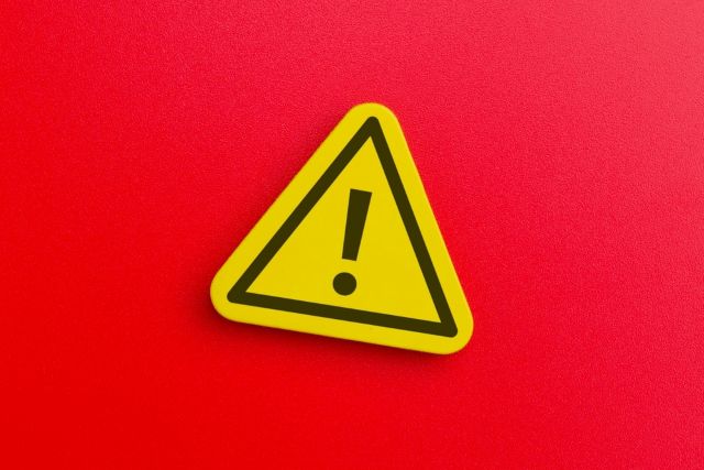 赤い背景の前にある注意マーク