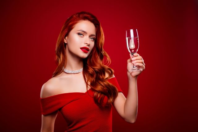 シャンパングラスを持つ赤いドレスの女性