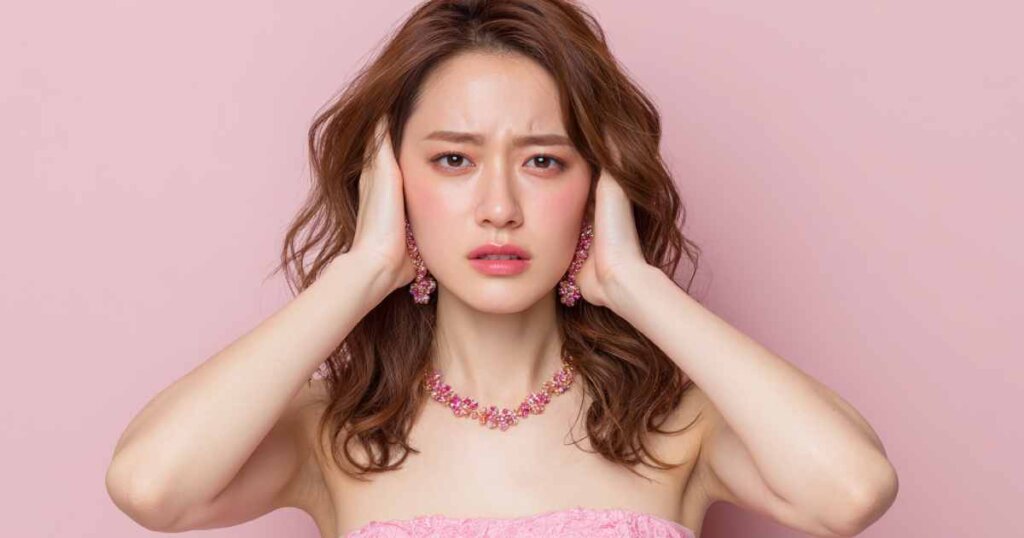 両手で耳をふさいでいる女性