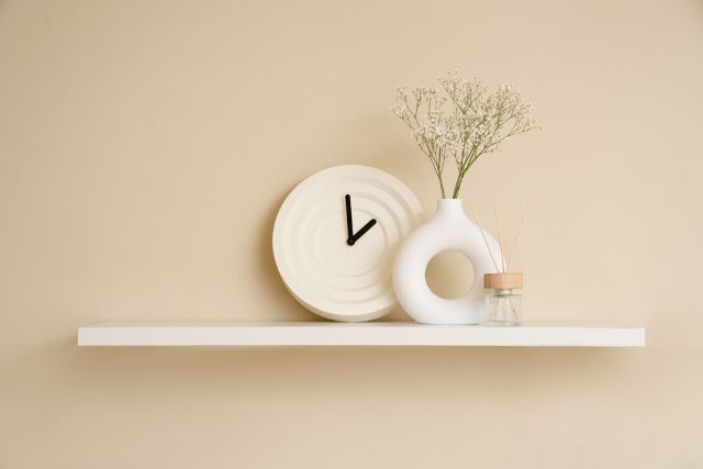 壁に置かれた時計と花瓶に入った花