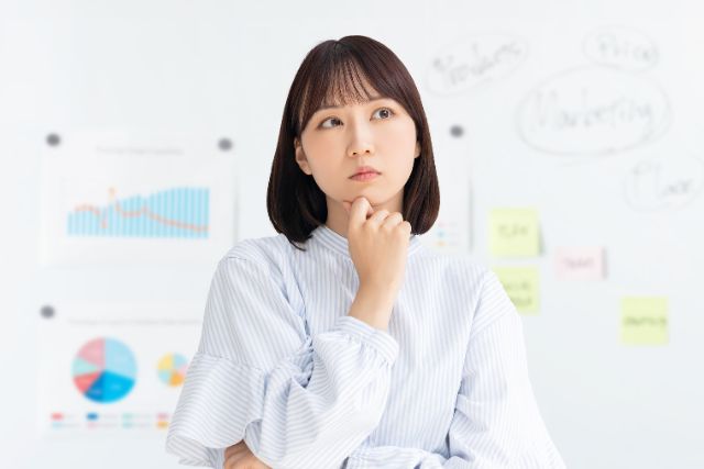 顎を触って悩む様子の女性