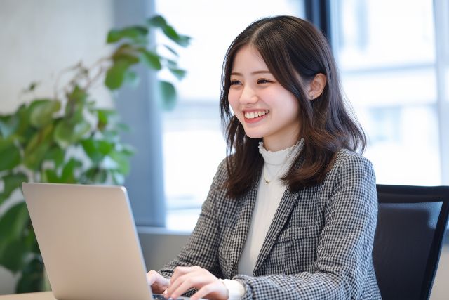 オフィスでPC操作をする笑顔の女性