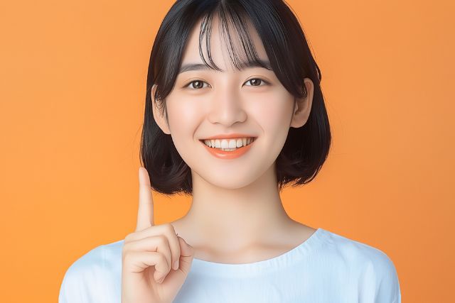 人差し指をたてて微笑むボブヘアの女性