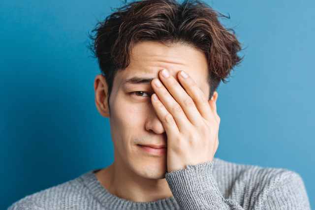 片目を抑える男性