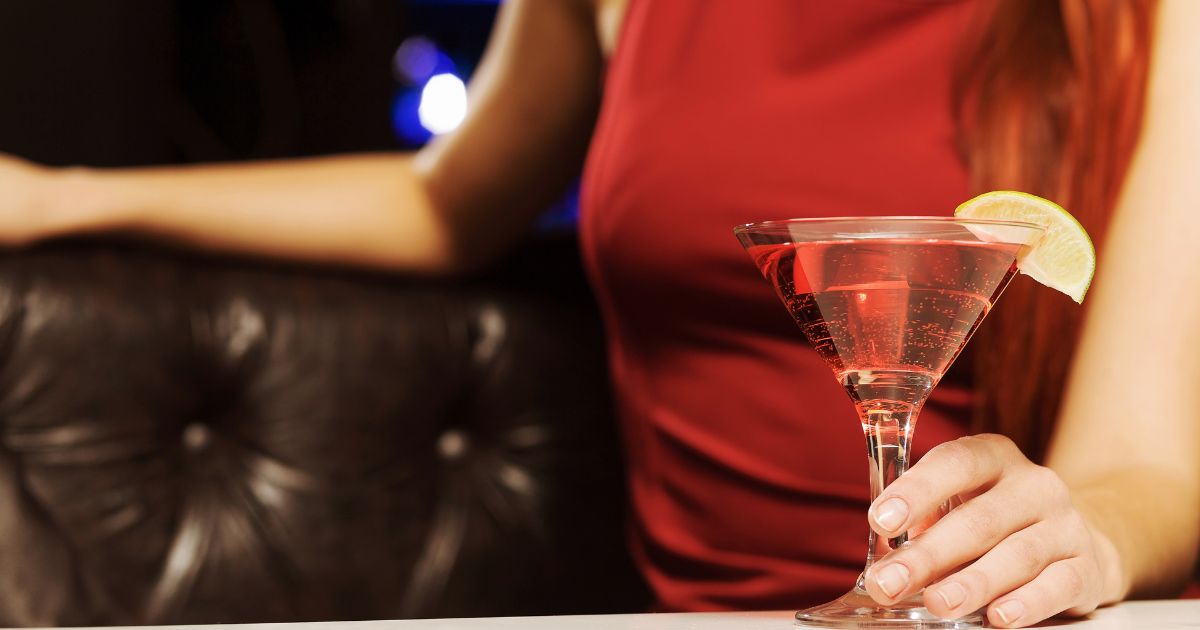 赤いドレスを着た女性がお酒を左手に持っている様子