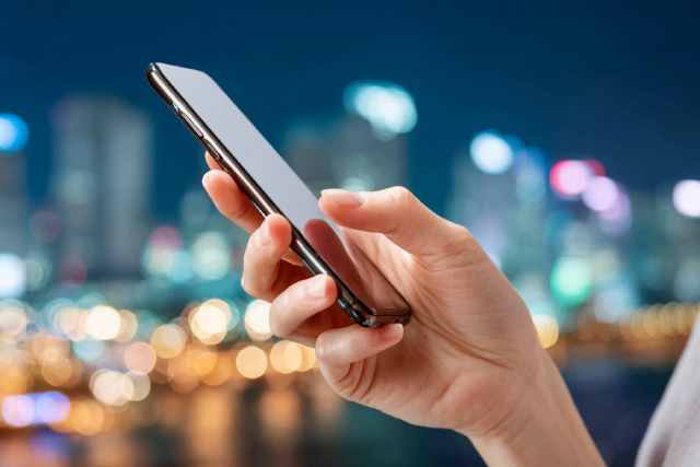 夜景の前でスマホを持つ女性の手