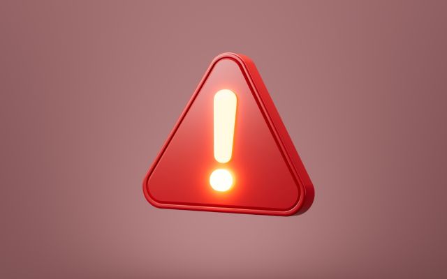 暗い色の背景の前にある光っている赤い注意マーク