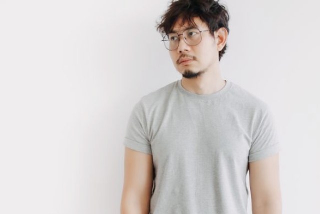 グレーのTシャツをきて唖然として立っている日本人の男性