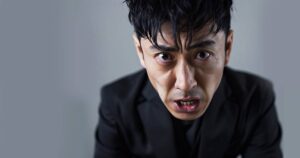 黒いスーツを着た中年の強面の日本人男性の顔のアップ