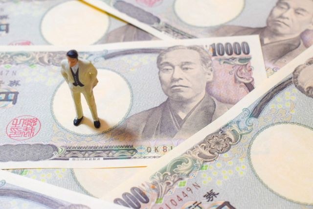 大量の一万円札と男性の人形