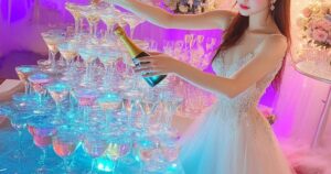 虹色のシャンパンタワーの前に立つドレス姿のキャバ嬢