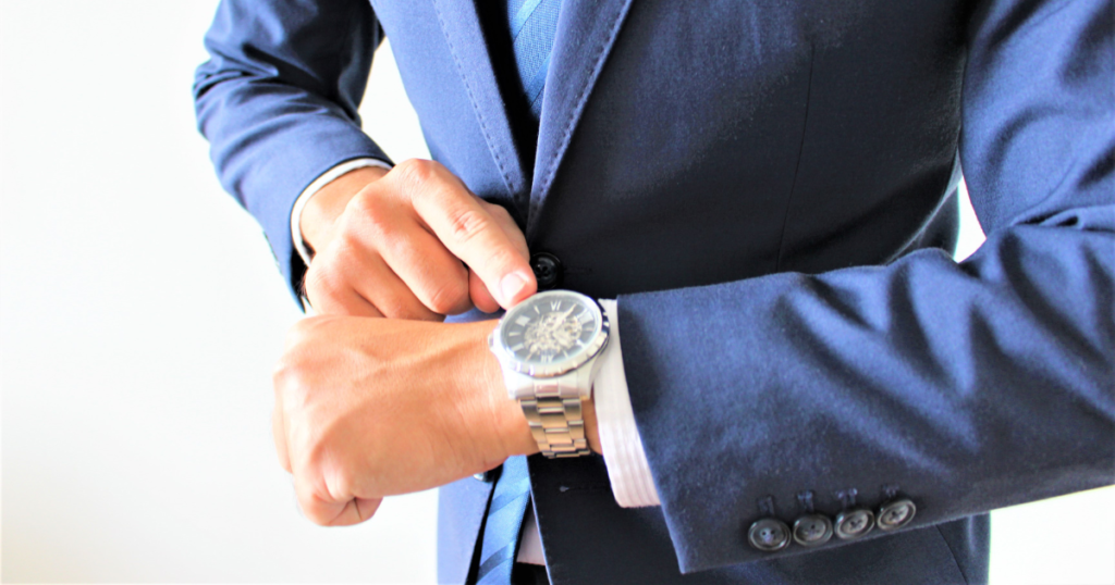 腕時計の時間を確認するスーツの男性