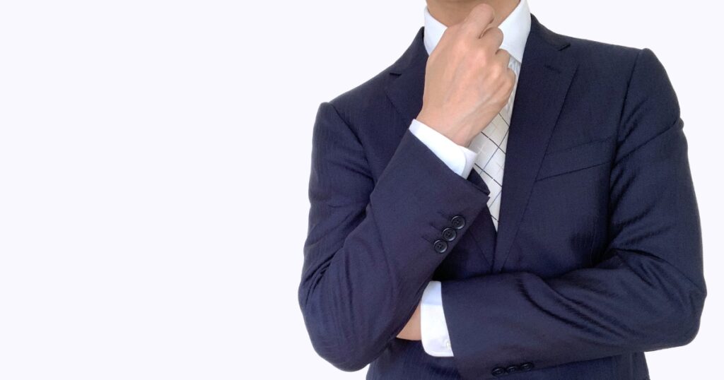 腕組みして考えるスーツの男性