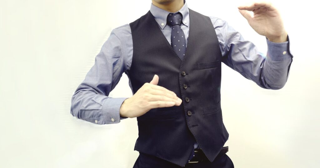 ベスト姿の男性がジェッスチャーをしている様子