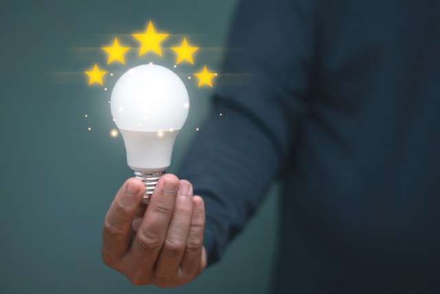 ビジネススーツの男性が光る電球を持つ様子