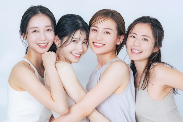 4人の若い女性が仲良さそうに密着して微笑んでいる