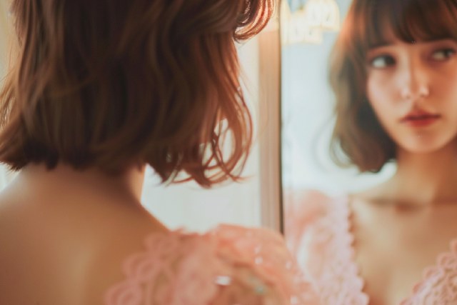 鏡の前に立つピンクのドレスのミディアムヘアのキャバ嬢