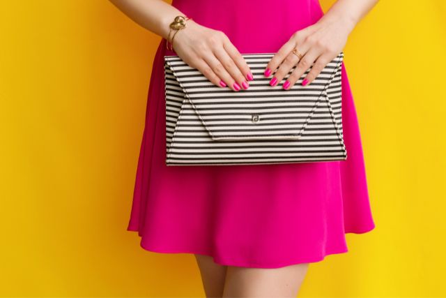 ストアイプのポーチを手に持つピンク色のドレスの女性