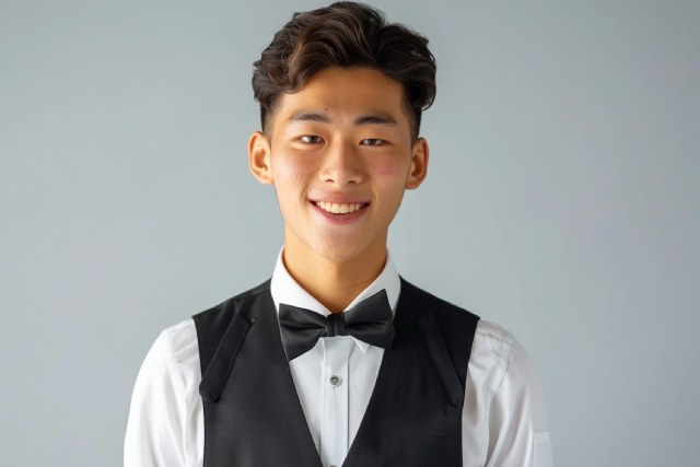 黒いベストを着て黒い蝶ネクタイを付けた黒髪の男性