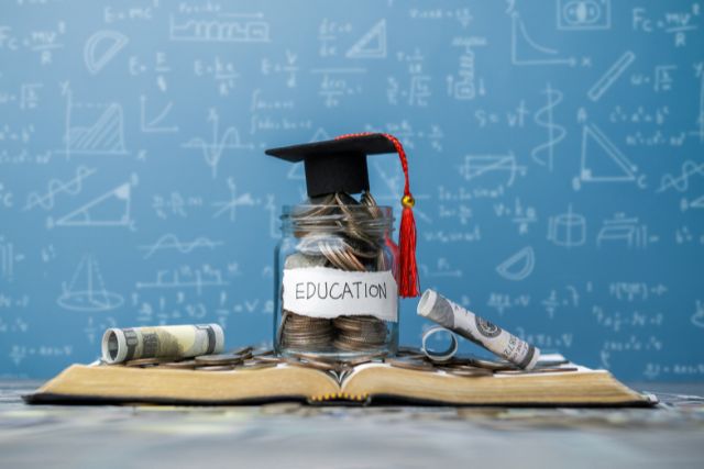 帽子をかぶせた「education」と書かれたラベルの中に詰まっているお金