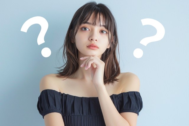 オフショルダーの黒いワンピースを着たセミロングの若い女性とクエスチョンマーク