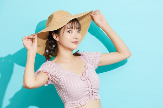 麦わら帽子をかぶって微笑む日本人女性と水色の背景