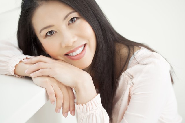 机にもたれかかって微笑む日本人の女性