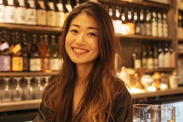 たくさんのお酒が並んでいるスナックで働く笑顔の大人の女性