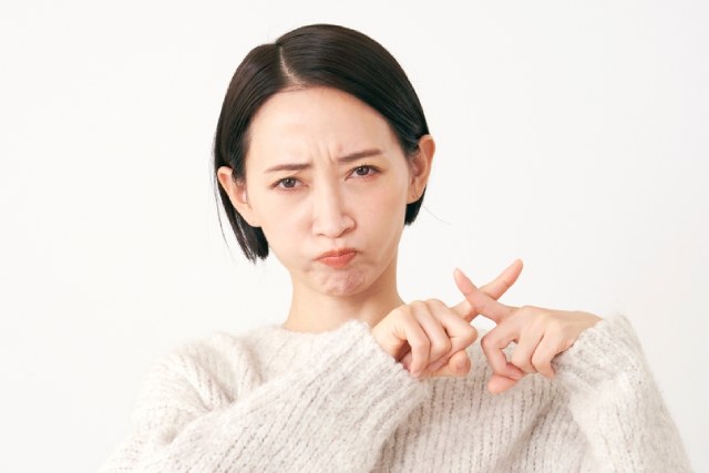 30代後半の日本人の女性が両指をクロスしてバツマークを作っている様子