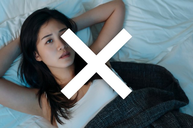 ベッドに寝転び考え込む若い日本人の女性とバツマーク