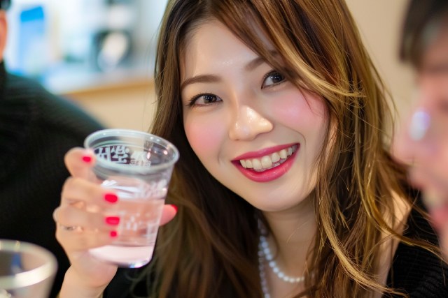 お酒のグラスをもって笑う若い日本人の女性