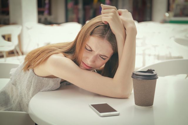 テーブルの上に伏せて悩んでいる女性