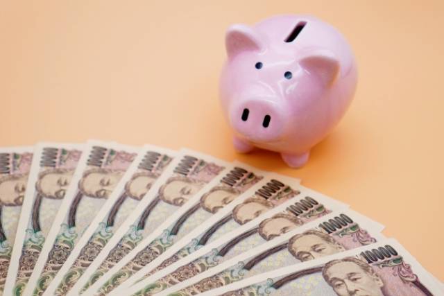 ピンクのブタの貯金箱と複数の一万円札
