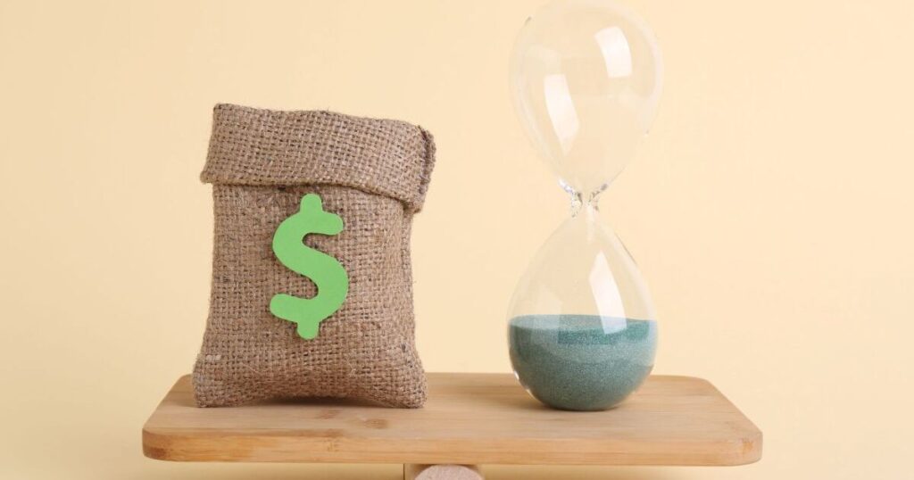 天秤に乗るドル袋と砂時計