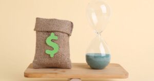 天秤に乗るドル袋と砂時計